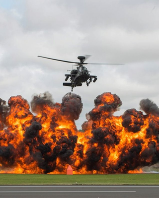 Illustration for article titled Here's an Apache attack helicopter flying away from a monster explosion